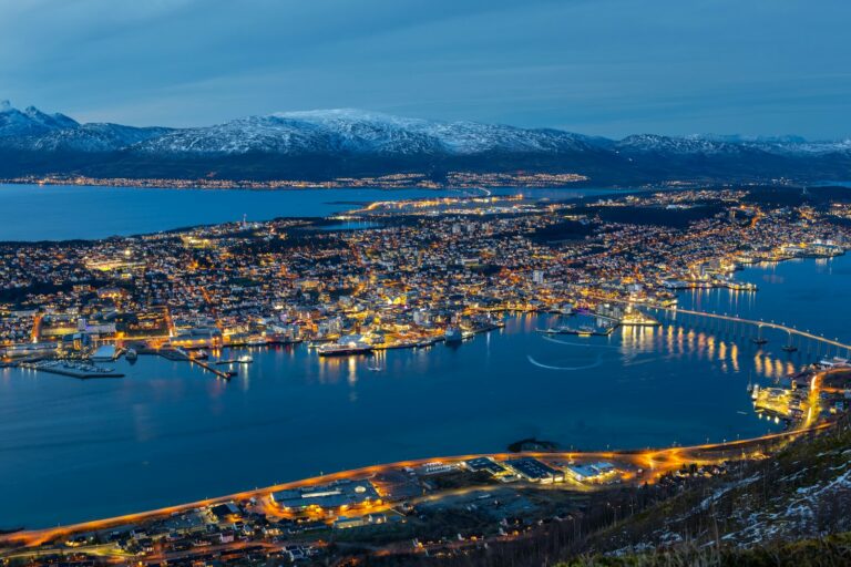 Tromsø by natt sett fra Fløya, med fjell i bakgrunnen